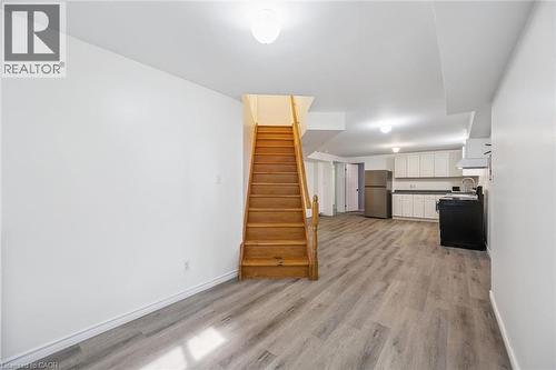 Hardwood staircase, wood-finish flooring, white cabinetry, stainless steel refrigerator, and recessed lighting - 233 Dearborn Boulevard Unit# Lower, Waterloo, ON 