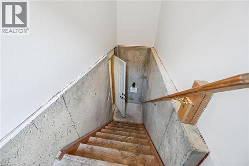 Wood-finish staircase with solid concrete walls and a natural wood handrail - 233 Dearborn Boulevard, Waterloo, ON 