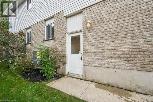 Brick and siding exterior with multiple windows, a white entry door, and a concrete pathway - 233 Dearborn Boulevard, Waterloo, ON 