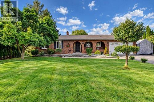 Brick exterior with arched entryway, attached garage, and mature landscaping - 1370 Thorman Place, Cambridge, ON 
