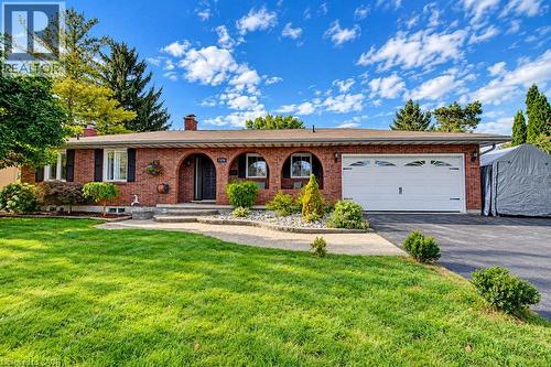 Brick exterior with arched entryways, integrated single-car garage, established front landscaping, and a paved driveway - 1370 Thorman Place, Cambridge, ON 