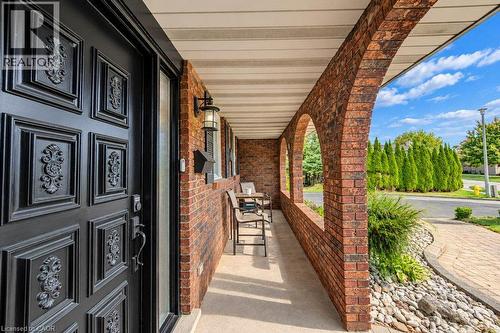 Porch entry with an ornate black door, brick archways, recessed lighting, and an exterior wall lantern - 1370 Thorman Place, Cambridge, ON 