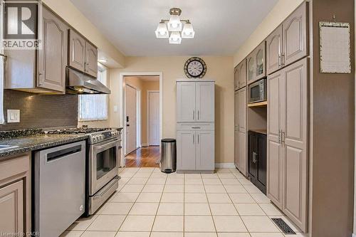 Kitchen featuring stainless steel appliances, grey cabinetry, dark speckled countertops, and a white tile floor - 1370 Thorman Place, Cambridge, ON 