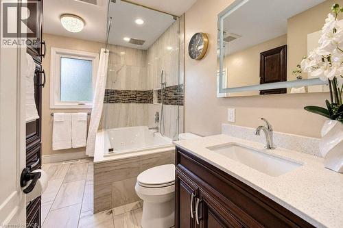 Walk-in shower with glass enclosure, built-in bathtub, wood-finish vanity with countertop, and large framed mirror - 1370 Thorman Place, Cambridge, ON 