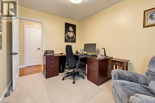 Carpeted room with a solid-core interior door featuring matte black hardware, and an adjacent entryway with wood-finish flooring - 1370 Thorman Place, Cambridge, ON 