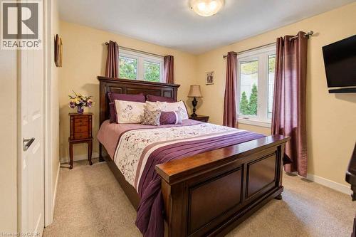 Carpeted bedroom with a built-in wall-mounted television and two windows - 1370 Thorman Place, Cambridge, ON 
