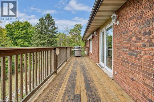 Expansive wood deck with a wood railing, brick exterior, and multiple glass panel doors - 1370 Thorman Place, Cambridge, ON 