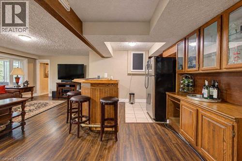 Wood-finish flooring, built-in wet bar, recessed lighting, and wood cabinetry with glass-front uppers - 1370 Thorman Place, Cambridge, ON 
