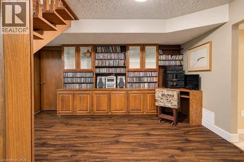 Wood-finish flooring, built-in wooden cabinetry with glass-front display cabinets, and a wooden open staircase with balusters - 1370 Thorman Place, Cambridge, ON 