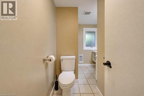 White toilet with tiled flooring, neutral wall tones, and an opaque window - 1370 Thorman Place, Cambridge, ON 