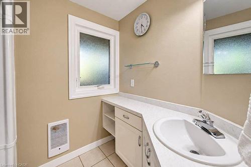 White window trim, an integrated sink basin, a wall-mounted glass shelf, and cabinet storage with brushed nickel hardware - 1370 Thorman Place, Cambridge, ON 
