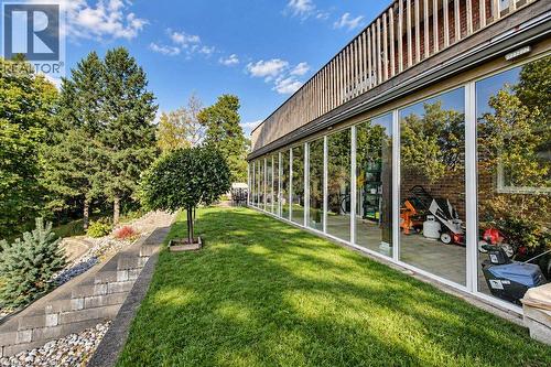 Expansive glass wall, manicured lawn, tiered landscaping, mature trees, and a slatted wood upper facade - 1370 Thorman Place, Cambridge, ON 