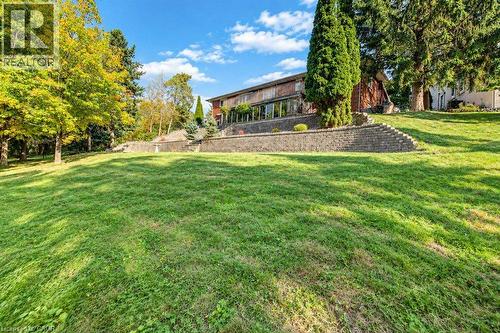 Expansive sloped lawn with mature trees and a multi-level retaining wall - 1370 Thorman Place, Cambridge, ON 