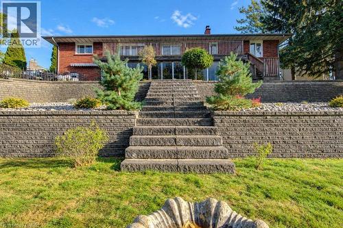 Brick exterior with multi-level retaining walls, integrated stone steps, and a walk-out lower level - 1370 Thorman Place, Cambridge, ON 