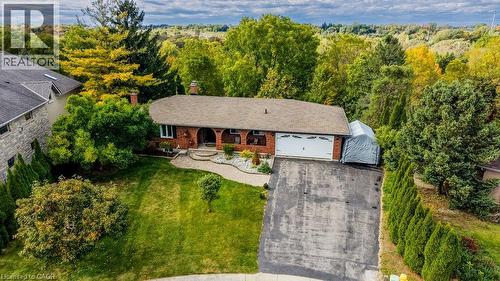 Brick exterior with white garage door, asphalt driveway, and mature landscaping - 1370 Thorman Place, Cambridge, ON 