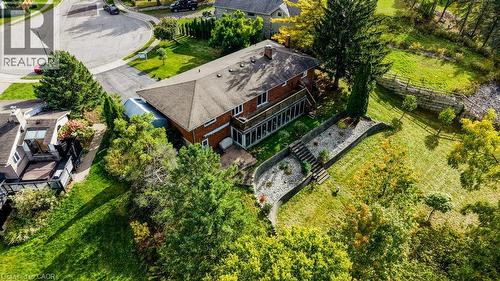 Red brick exterior featuring a multi-level deck, an enclosed patio, and a sloped landscape with a retaining wall and built-in steps - 1370 Thorman Place, Cambridge, ON 