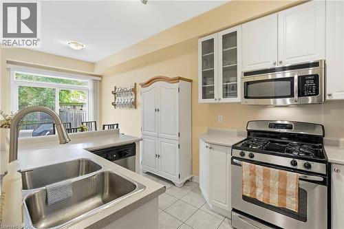 Kitchen featuring white cabinetry, stainless steel appliances, a double basin sink with a high-arch faucet, and light-toned countertops - 1076 Ryckman Common, Burlington, ON 