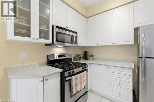 White cabinetry, light-toned countertops, stainless steel appliances, and glass-front upper cabinets - 1076 Ryckman Common, Burlington, ON 