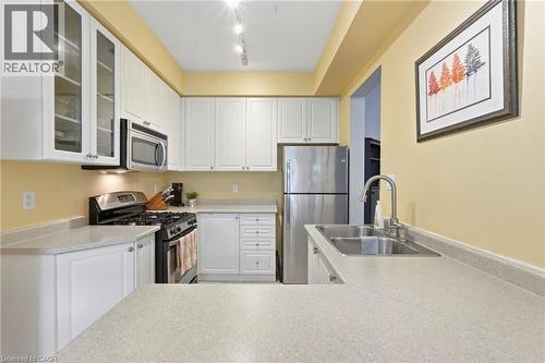 Contemporary kitchen featuring white cabinetry, stainless steel appliances, light-toned countertops and a double basin sink - 1076 Ryckman Common, Burlington, ON 