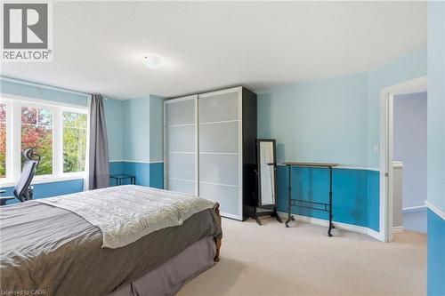 Expansive window offering natural illumination, light-toned carpet flooring, white trim, and a wardrobe with frosted sliding doors - 1076 Ryckman Common, Burlington, ON 