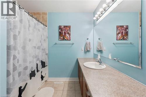 Bathroom featuring a single basin vanity, integrated mirror, multi-bulb vanity lighting, and tiled flooring - 1076 Ryckman Common, Burlington, ON 