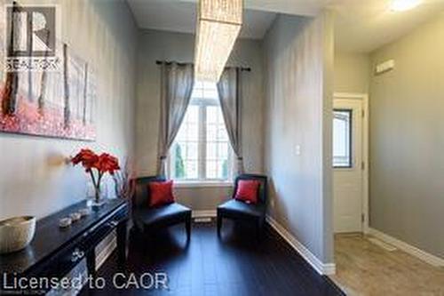 Wood-finish flooring, central window with grid pattern, and a prominent rectangular light fixture - 28 Madonna Drive, Hamilton, ON 