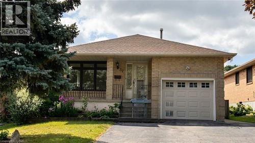 Brick exterior with a single-car garage featuring window inserts - 37 Elora Drive, Hamilton, ON 