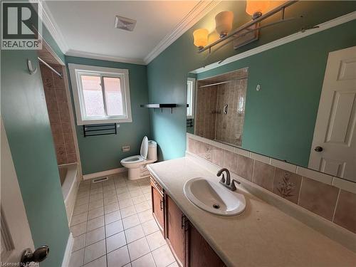 Bathroom featuring a vanity with an integrated sink, a large mirror, a tiled bathtub and shower combination, a toilet, and a window - 37 Elora Drive, Hamilton, ON 