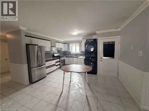Kitchen with white tile flooring, stainless steel appliances, white cabinetry with dark wood-finish accents, and a tile backsplash - 37 Elora Drive, Hamilton, ON 