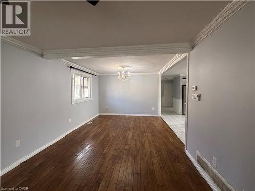 Wood-finish flooring, white trim, crown molding, and a chandelier lighting fixture - 37 Elora Drive, Hamilton, ON 