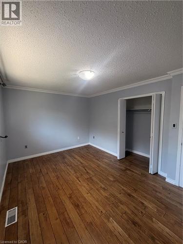 Wood-finish flooring, light gray wall paint, white crown molding, ceiling light fixture, and an open closet - 37 Elora Drive, Hamilton, ON 