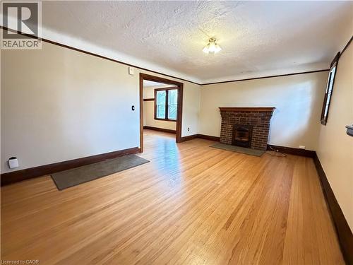 Wood-finish flooring, brick fireplace with mantel, ceiling-mounted light fixture, and wood trim detailing - 507 Aberdeen Avenue, Hamilton, ON 