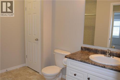 Bathroom featuring a white vanity with a dark countertop, an integrated sink, and a framed mirror - 507 Beaumont Crescent, Kitchener, ON 