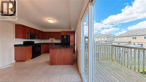 Kitchen featuring wood-finish cabinetry, dark countertops, and tile flooring - 250 Parkvale Drive, Kitchener, ON 