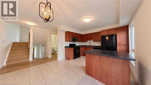 Kitchen with wood-finish cabinetry, black appliances, and a central island - 250 Parkvale Drive, Kitchener, ON 