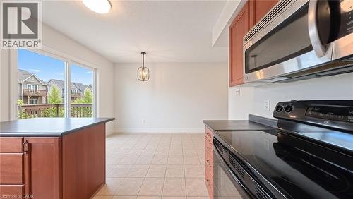 Kitchen featuring wood-finish cabinetry, stainless steel microwave, black electric range, and dark countertops - 250 Parkvale Drive, Kitchener, ON 