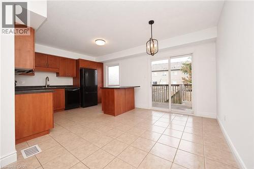 Kitchen with wood-finish cabinetry, black appliances, and a central island with a dark countertop - 250 Parkvale Drive, Kitchener, ON 