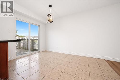 Sliding glass patio doors, tiled flooring, contemporary pendant light fixture, wood-finish flooring, and a dark countertop - 250 Parkvale Drive, Kitchener, ON 