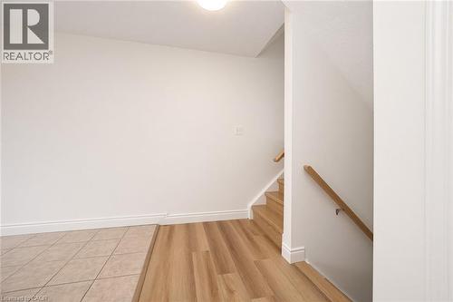 Wood-finish flooring, tiled entry, light wood handrails, and white painted walls - 250 Parkvale Drive, Kitchener, ON 