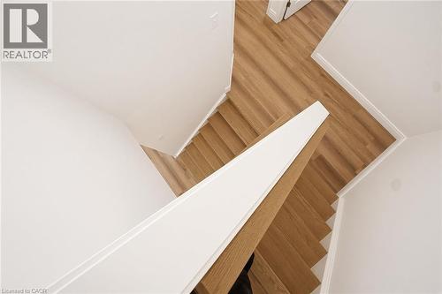 Wood-finish flooring with white trim and a contrasting white and wood-finish stair railing - 250 Parkvale Drive, Kitchener, ON 