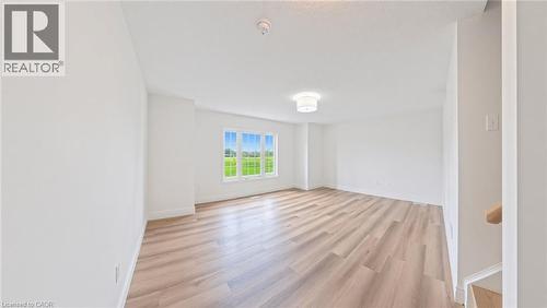 Expansive room featuring wood-finish flooring, a large multi-pane window, and a flush-mount ceiling light fixture - 250 Parkvale Drive, Kitchener, ON 