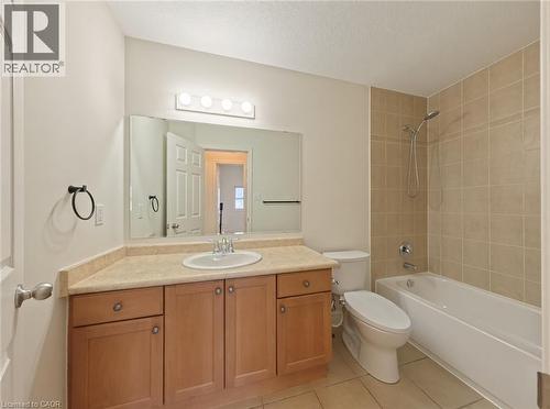 Tiled flooring, vanity with integrated sink, large mirror, full bathtub with tiled surround, and a modern toilet - 250 Parkvale Drive, Kitchener, ON 