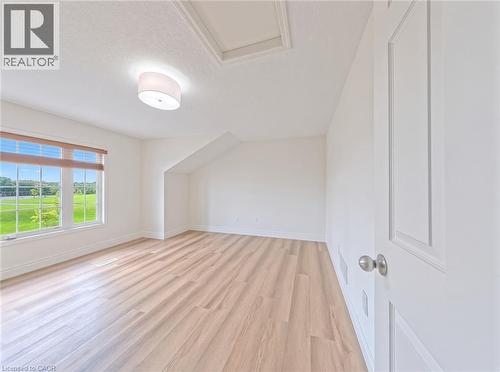 Expansive room featuring wood-finish flooring, a contemporary ceiling light fixture, a large window, and a white paneled door - 250 Parkvale Drive, Kitchener, ON 