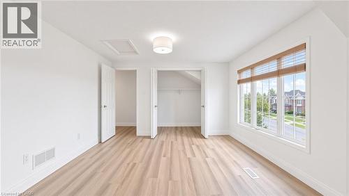 Expansive room featuring wood-finish flooring, a large multi-pane window, and a built-in closet - 250 Parkvale Drive, Kitchener, ON 