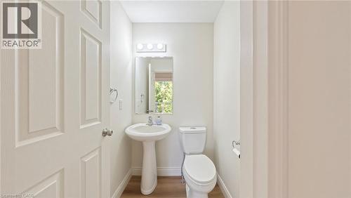 Pedestal sink with chrome faucet, mirror with decorative border, and wood-finish flooring - 250 Parkvale Drive, Kitchener, ON 
