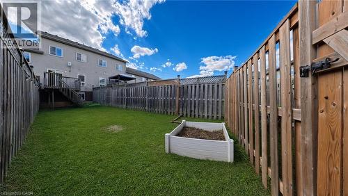 Expansive backyard featuring a manicured lawn, full privacy fencing, and a raised garden bed - 250 Parkvale Drive, Kitchener, ON 