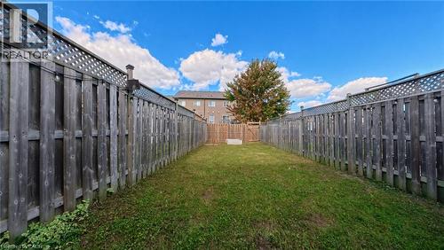 Spacious backyard featuring a grass lawn, wood privacy fencing, and rear gate access - 250 Parkvale Drive, Kitchener, ON 