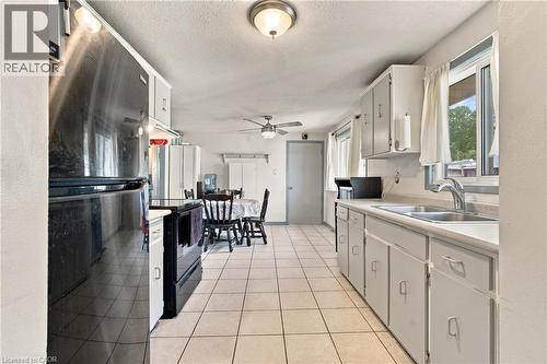 Kitchen featuring white cabinetry, tile flooring, and a double-basin stainless steel sink - 135 Cedarhill Crescent, Kitchener, ON 