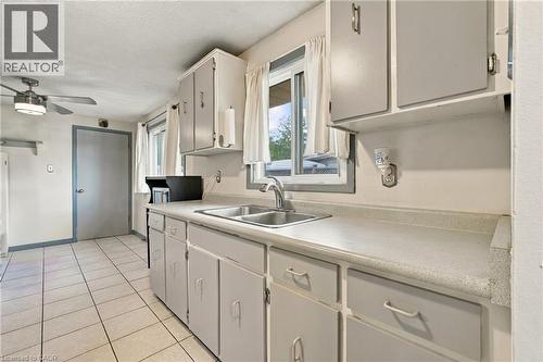 White tile flooring, dual basin stainless steel sink, light-toned cabinetry, light-toned countertops, and a ceiling fan with integrated lighting - 135 Cedarhill Crescent, Kitchener, ON 