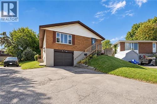 Brick exterior with white siding, attached garage, and a sloped, landscaped front yard - 135 Cedarhill Crescent, Kitchener, ON 